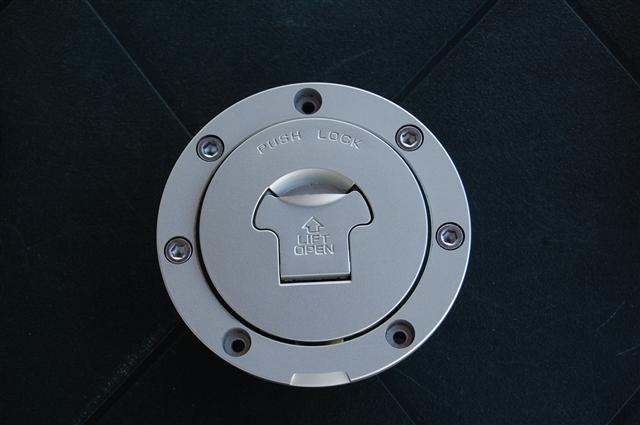 Nyckel och tanklock behövs. Locket sitter fast med 3 insex skruvar. Du ser de tre tomma hålen